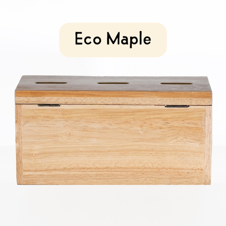 Puede incluir: Una caja de madera con tapa abatible y tres ranuras en la parte superior. La caja est&aacute; hecha de madera de arce ecol&oacute;gica y tiene un acabado de madera natural. El texto "Eco Maple" est&aacute; impreso en una etiqueta encima de la caja.