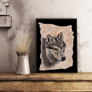 May include: A framed print of a wolf's head on textured, parchment-like paper. The wolf has a grey and black coat with bright yellow eyes. The background is black.