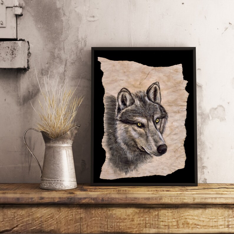 May include: A framed print of a wolf's head on textured, parchment-like paper. The wolf has a grey and black coat with bright yellow eyes. The background is black.