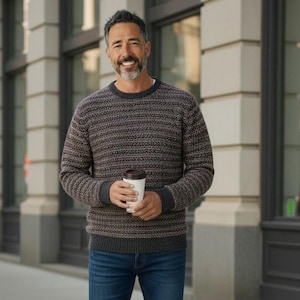 May include: A long-sleeve crew neck sweater featuring a horizontal knit pattern in shades of charcoal, brown, and muted red, paired with dark blue denim jeans. The sweater has solid charcoal ribbed cuffs and a matching ribbed crew neckline.