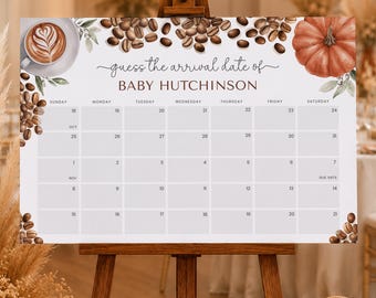 May include: A rectangular sign on a wooden easel featuring a calendar titled "guess the arrival date of BABY HUTCHINSON". The design includes illustrations of coffee beans, a latte with foam art, and a pumpkin, set against a white background.
