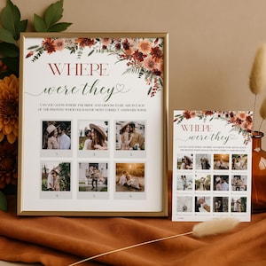 Op de afbeelding: Een ingelijste trouwspelkaart met de tekst "WHERE were they" en zes foto's. Een kleinere bijpassende kaart is ook aanwezig. De kaarten hebben een bloemmotief in rood, oranje en bruin. Het spel daagt gasten uit om de locaties op de foto's te raden.