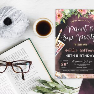 May include: A black and pink invitation to a paint and sip party to celebrate Natalie Williams' 45th birthday. The invitation features a watercolour background with floral accents, paintbrushes, and champagne glasses. The party is scheduled for Saturday, 28th August at 7:00 pm at The Book Nook & Java Shop in Montague, MI. RSVP by 18th August to Susan at 231-234-5678.
