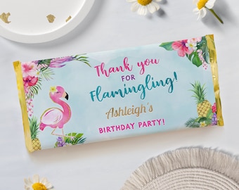 May include: A blue and white thank you chocolate bar wrapper with a pink flamingo, tropical flowers, and pineapple. The text reads "Thank you for flamingling! Ashleigh's Birthday Party!"