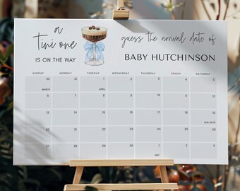 May include: A white calendar with a blue ribbon and a glass of coffee with cream on top. The calendar is for guessing the arrival date of Baby Hutchinson. The calendar starts on March 30th and ends on May 3rd.