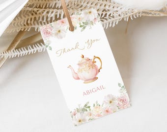 Puede incluir: Etiqueta de agradecimiento para una fiesta de té rosa y dorada con una ilustración de acuarela de una tetera y flores. La etiqueta dice "Gracias" y "Abigail".