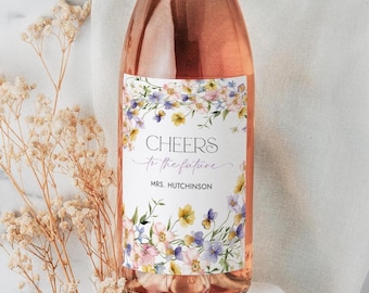 Könnte beinhalten: Eine Flasche Roséwein mit einem floralen Etikett, auf dem "Cheers to the future" und "Mrs. Hutchinson" steht.