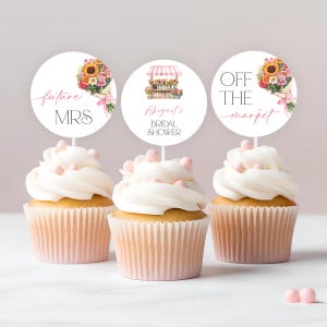 May include: Three cupcake toppers with floral designs. The first topper says "future MRS" in pink script. The second topper says "Abigail's Bridal Shower" in pink script. The third topper says "Off the market" in pink script.