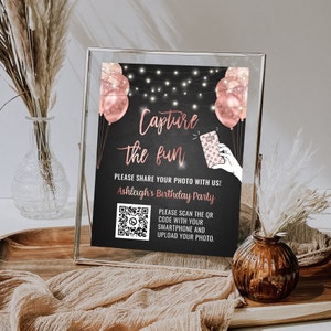 Peut inclure: Une pancarte en ardoise noire avec des lumières blanches et des ballons rose gold qui dit "Capture the fun".  La pancarte comprend également un code QR et le texte "Veuillez partager votre photo avec nous ! Ashleigh's Birthday Party. Veuillez scanner le code QR avec votre smartphone et télécharger votre photo."