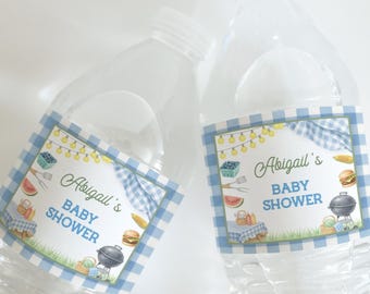 Puede incluir: Dos botellas de agua de plástico transparente con etiquetas para un baby shower. Las etiquetas tienen un borde de cuadros azules y blancos y presentan ilustraciones de comida de picnic, una parrilla y el texto "Baby Shower de Abigail".