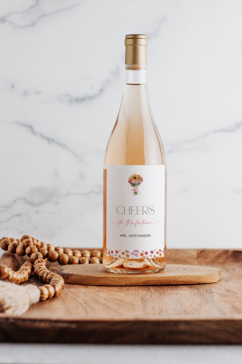 Peut inclure: Une bouteille de vin ros&eacute; avec une &eacute;tiquette &agrave; motif floral qui dit "Cheers to the future" et "Mrs. Hutchinson".