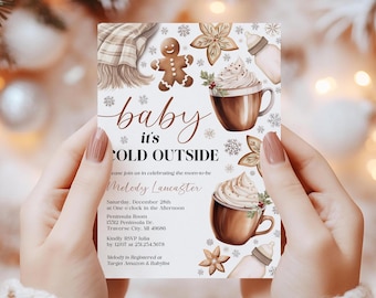 May include: A white baby shower invitation with a winter theme. The invitation features a gingerbread man, snowflakes, and illustrations of hot chocolate with whipped cream. The text on the invitation reads "baby it's cold outside" and includes the name "Melody Lancaster".