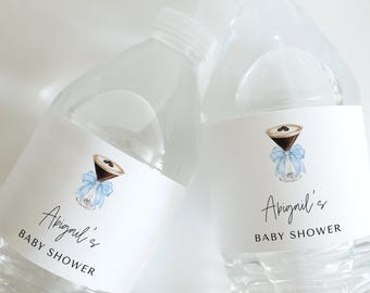 May include: Two clear plastic water bottles with white labels. The labels feature a watercolor illustration of a martini glass with a blue ribbon and the text "Abigail's Baby Shower".