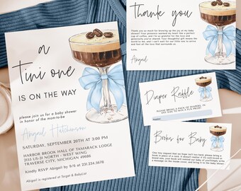 May include: A baby shower invitation with a blue and white color scheme. The invitation features a cocktail glass with a blue bow and a coffee drink inside. The text on the invitation reads "A Tini One Is On The Way".