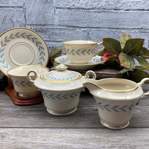May include: A set of vintage teacups and saucers with a blue and gold leaf design. The set includes a teapot, creamer, and sugar bowl.
