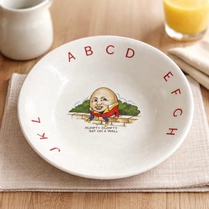May include: White ceramic bowl with red alphabet letters around the rim. The bowl features a Humpty Dumpty illustration with the text "HUMPTY DUMPTY SAT ON A WALL".