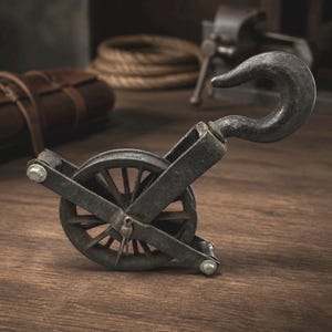 May include: A vintage-style metal pulley with a large hook and a spoked wheel. The pulley is dark gray and sits on a wooden surface. The design evokes an industrial or nautical theme.