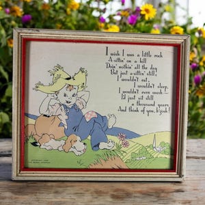 Könnte beinhalten: Eine gerahmte Vintage-Illustration eines Jungen mit Strohhut und Latzhose, der mit einem Hund auf einem Hügel sitzt. Die Illustration wird von einem Gedicht begleitet, das lautet: "Ich wünschte, ich wäre ein kleiner Stein, der auf einem Hügel sitzt, den ganzen Tag nichts tut, sondern nur still sitzt, ich würde nicht essen. Ich würde nicht schlafen. Ich würde nicht einmal waschen - ich würde einfach nur tausend Jahre still sitzen und an dich denken, verdammt!"