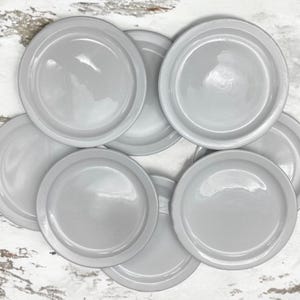 May include: A set of eight gray metal jar lids. The lids are round and have a smooth, shiny finish.