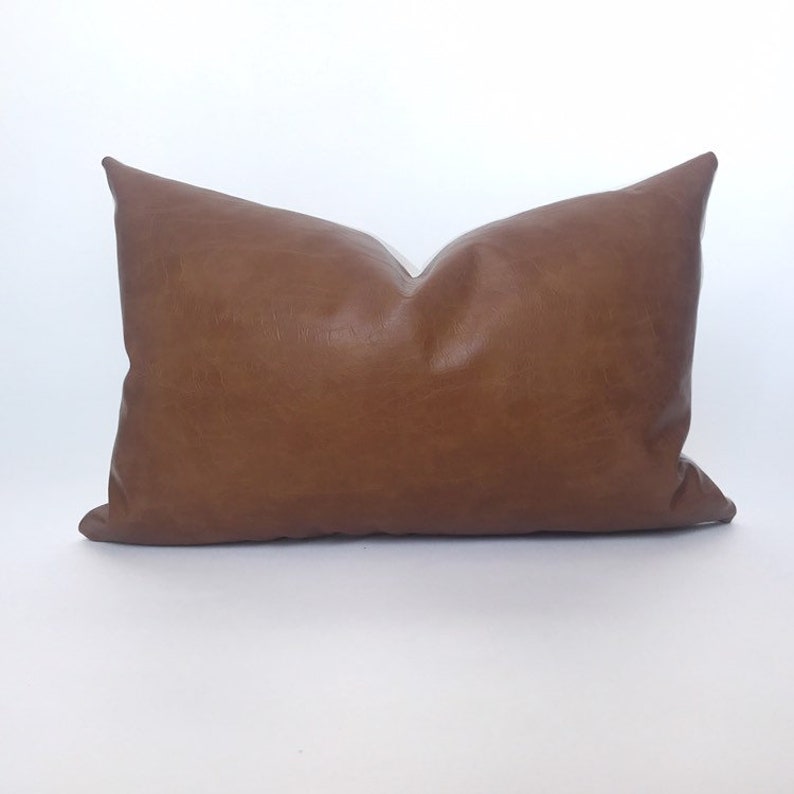 May include: A brown leather lumbar pillow with a smooth, textured surface.