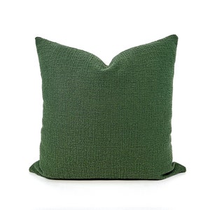 May include: A dark green square pillow with a textured fabric. The pillow is made of a soft, comfortable material and is perfect for adding a touch of color and style to any room.