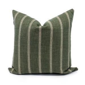 May include: A green and white striped throw pillow with a subtle texture. The pillow is made of a soft, woven fabric and has a simple, elegant design.