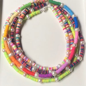 May include: Multicolored layered necklace with white pearl beads. The necklace is made of colorful, striped, round beads.