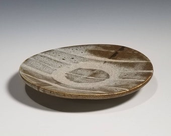 May include: A white and brown ceramic plate with a wavy design. The plate has a slightly raised rim and a smooth, glazed surface.