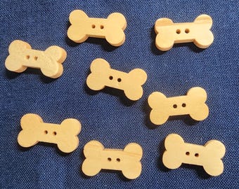 May include: Eight wooden bone-shaped buttons in a light brown color. The buttons have two holes each.
