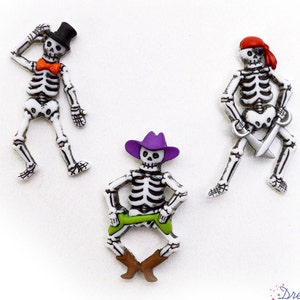 May include: Three skeleton buttons with different costumes. One skeleton is wearing a top hat and bow tie, another is wearing a pirate hat and holding a sword, and the third is wearing a purple cowboy hat and green pants.