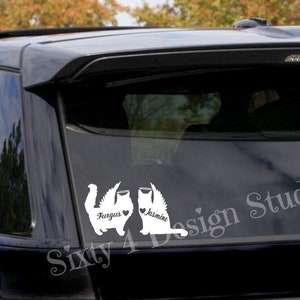 May include: White vinyl decal of two cats with wings and hearts, with the names Fergus and Jasmine, on the back window of a black car.