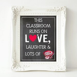 Puede incluir: Un letrero de pizarra enmarcado con texto blanco que dice "THIS CLASSROOM RUNS ON LOVE, LAUGHTER & LOTS OF" con un corazón rojo y un logotipo de Dr. Pepper Diet. El marco es blanco con detalles ornamentados.