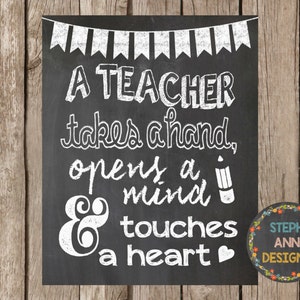 以下が含まれることがあります： 白い文字で「A TEACHER takes a hand, opens a mind & touches a heart」と書かれた黒板の看板。看板の上部には白い旗の装飾的な縁取りが施されている。右下には「STEPH ANN DESIGNS」という文字が書かれた小さな円がある。