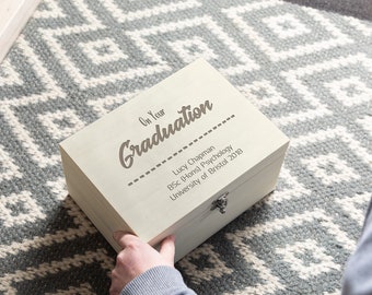 May include: A white wooden box with a hinged lid and a silver latch. The box is engraved with the text "On Your Graduation" and "Lucy Chapman BSc (Hons) Psychology University of Bristol 2018".