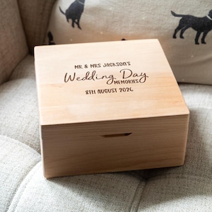 May include: A square light-coloured wooden keepsake box with a hinged lid. The top is engraved with the text MR & MRS JACKSON'S Wedding Day MEMORIES and the date 8TH AUGUST 2026. The box features a smooth finish and a small front notch for opening.