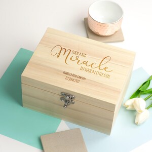 May include: A wooden keepsake box with a hinged lid and a silver latch. The box is engraved with the words "Such a big miracle in such a little girl" and the name "Isabella Rose Lawson" and the date "1st June 2017".
