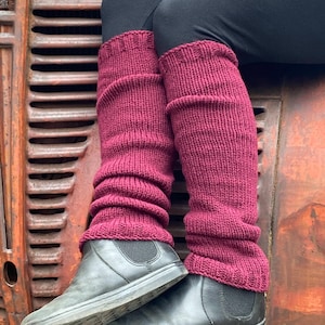 Op de afbeelding: Een paar bordeauxrode gebreide beenwarmers. De beenwarmers zijn gemaakt van een zacht, comfortabel garen en zijn perfect om je benen warm te houden in de winter.