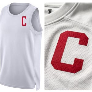 May include: White athletic tank top with a red "C" logo on the chest. The sleeveless shirt is made of a breathable, textured fabric. A close-up shows the red letter "C" on the white fabric.