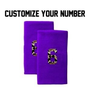 Peut inclure: Deux bracelets violets avec un numéro 6 à motif peau de serpent sur chacun. Personnalisez votre numéro.