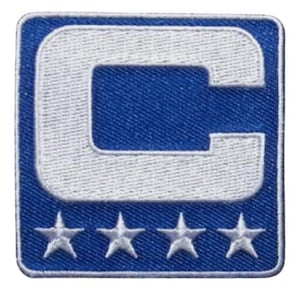 May include: Embroidered patch featuring a white letter "C" on a blue background, outlined in white. Four white stars are below the letter. The patch has a square shape with rounded corners.