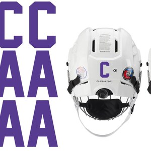 May include: White hockey helmets with black face masks, featuring purple letter decals. The helmets display the letters "C" and "A" in purple. The text "ALPHA ONE" is visible on the helmets.