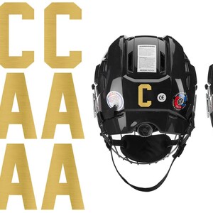 May include: Gold-colored hockey helmet letters and two black hockey helmets. The letters include multiple "C" and "A" characters. Two black hockey helmets are shown with the letters "C" and "A" on the back.