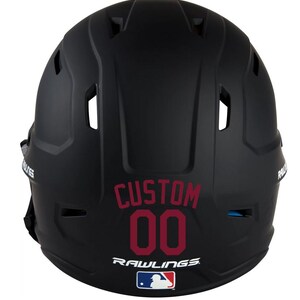 May include: Black baseball helmet with the word "CUSTOM" and the number "00" in maroon. The Rawlings logo and MLB logo are visible at the bottom. The helmet has several vents and is designed for protection.