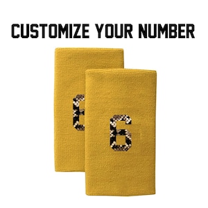 Peut inclure: Deux bracelets jaunes avec un numéro "6" en motif peau de serpent noir et brun sur chacun.