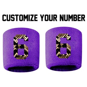 Peut inclure: Deux bracelets violets avec un motif de peau de serpent et le numéro 6 imprimé sur chacun.