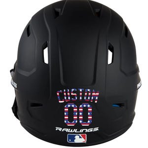May include: A black baseball helmet with the word "CUSTOM" and the number "00" in a red, white, and blue stars and stripes design. The Rawlings logo and MLB logo are visible at the bottom.