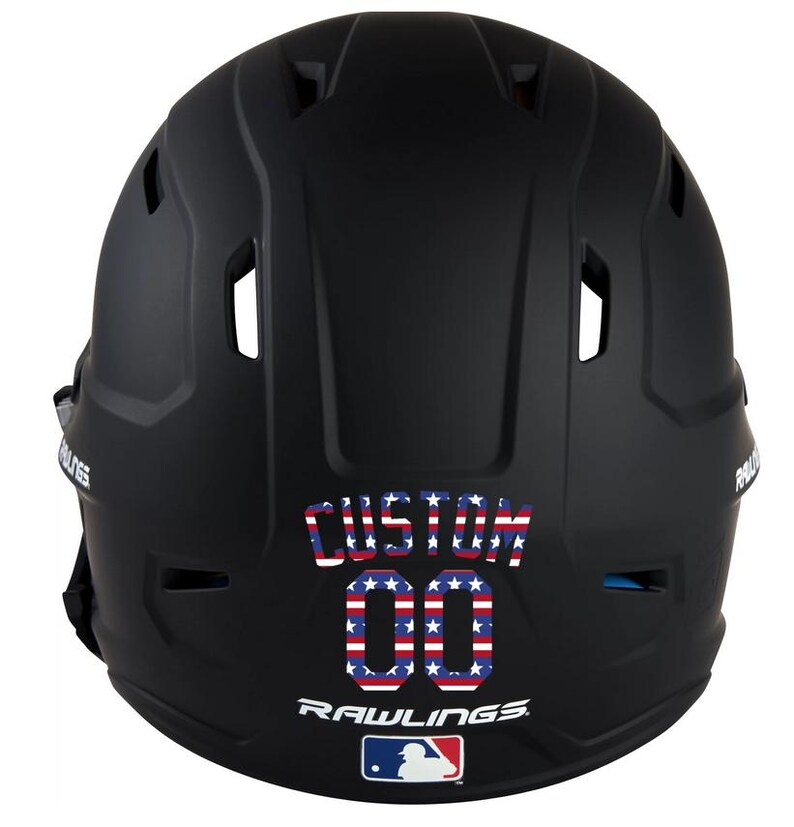 May include: A black baseball helmet with the word "CUSTOM" and the number "00" in a red, white, and blue stars and stripes design. The Rawlings logo and MLB logo are visible at the bottom.