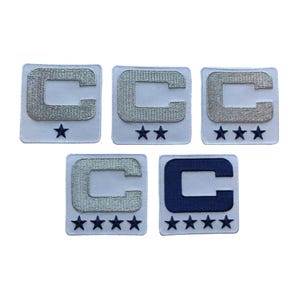 May include: Five embroidered patches with a white background. Each patch features a silver or navy blue letter "C" and a varying number of blue stars. The patches are square and have a white border.