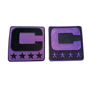 May include: Two square patches with a purple background and a black "C" design. The letter "C" is outlined in black and has four stars below it. The patches are embroidered.