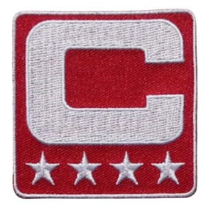 May include: A square red patch with a white embroidered letter "C" and four white stars at the bottom. The patch has a white border. The design is a classic emblem.